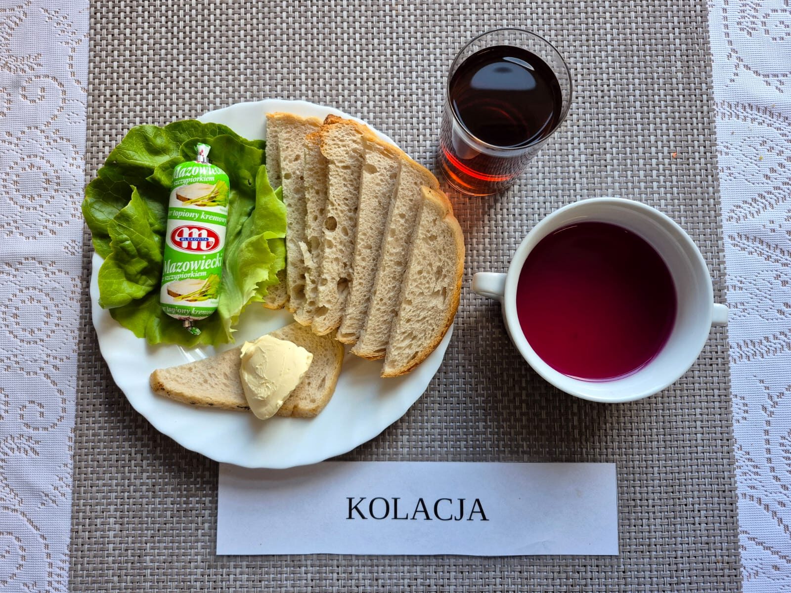 Na zdjęciu znajduję się posiłek w którego skład wchodzi Chleb pszenny, Margaryna Śniadaniowa, ser topiony, sałata masłowa oraz Herbata czarna