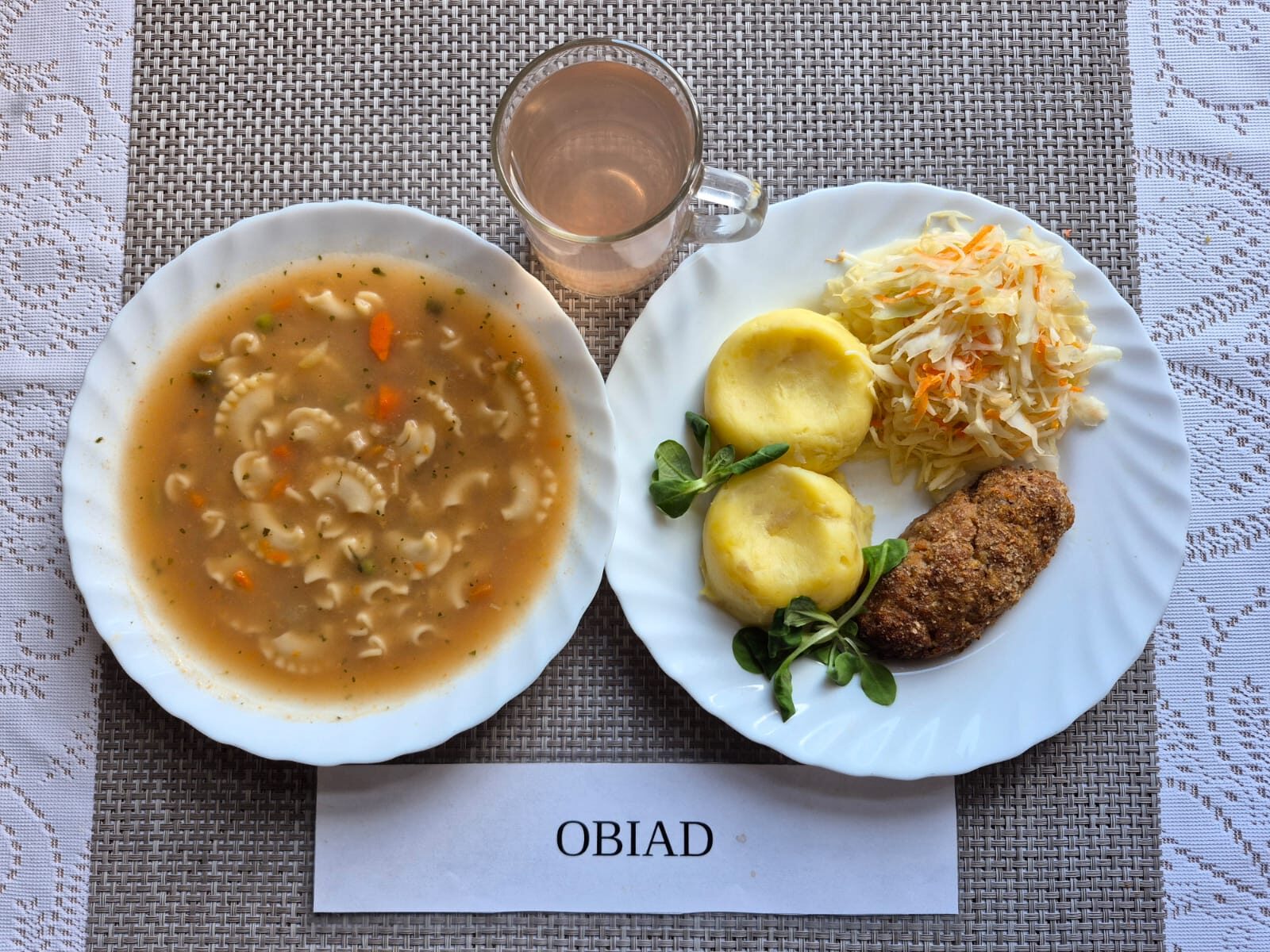 Na zdjęciu znajduję się posiłek w którego skład wchodzi Zupa ogonowa z makaronem, Sznycel smażony, Ziemniaki, Surówka z kapusty białej, z zalewą octową oraz Kompot z jabłek