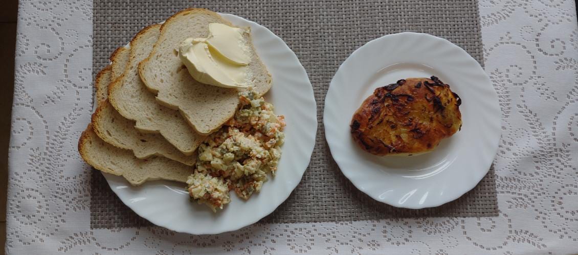 Na zdjęciu znajduję się posiłek w którego skład wchodzi Chleb pszenny, Margaryna Śniadaniowa, Sałatka jarzynowa, Wędlina oraz Herbata czarna