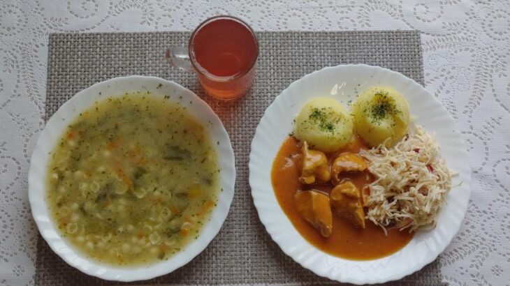 Na zdjęciu znajduję się posiłek w którego skład wchodzi Zupa porowa z makaronem, Ziemniaki, Kotlet drobiowy, Surówka z selera i jabłka z dodatkiem rodzynek oraz Kompot z jabłek