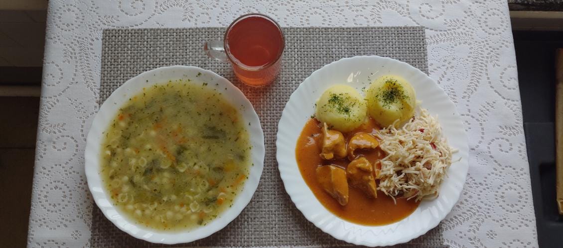 Na zdjęciu znajduję się posiłek w którego skład wchodzi Zupa porowa z makaronem, Ziemniaki, Kotlet drobiowy, Surówka z selera i jabłka z dodatkiem rodzynek oraz Kompot z jabłek