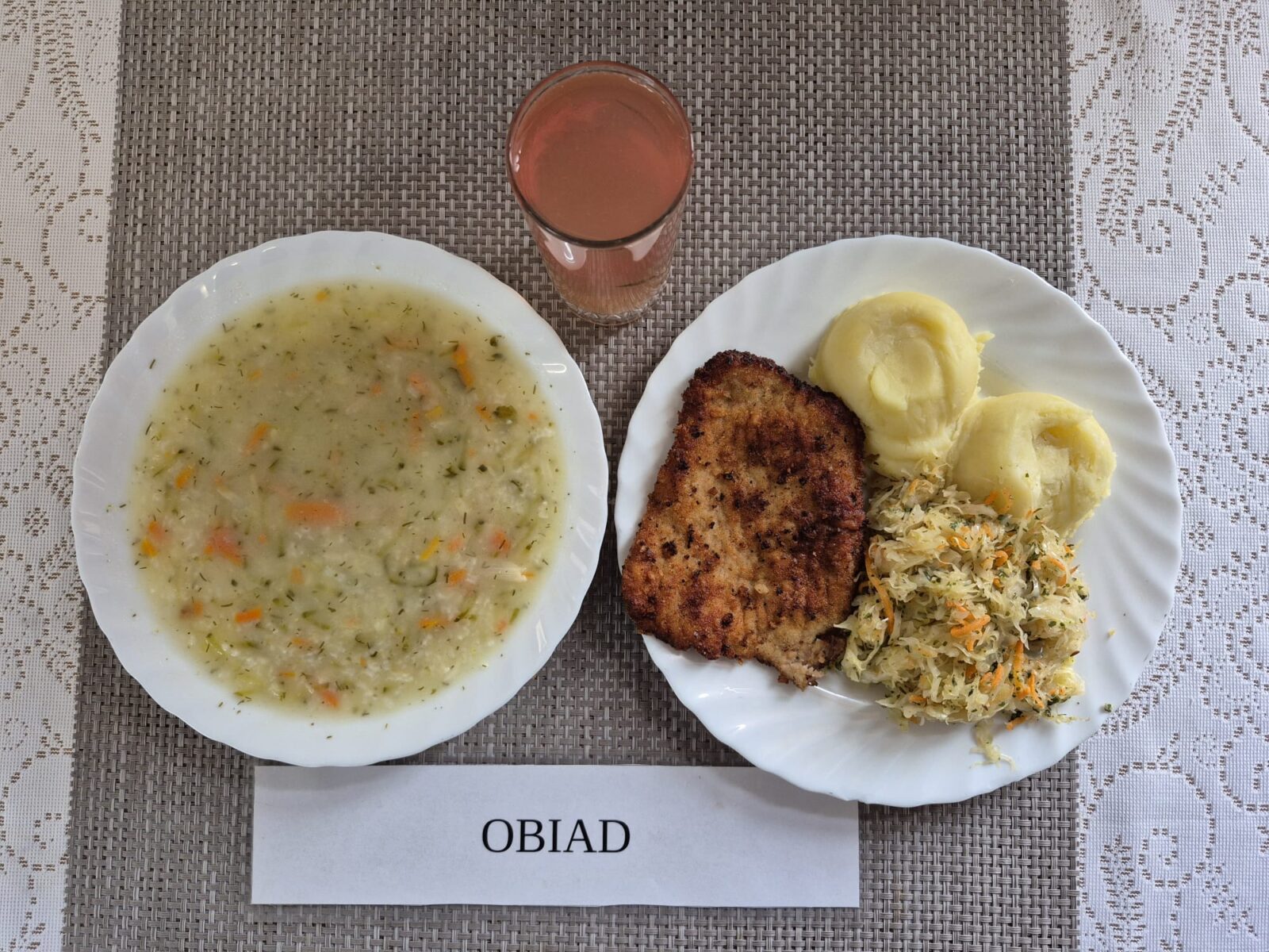 Na zdjęciu znajduję się posiłek w którego skład wchodzi Zupa ogórkowa z ryżem białym, Ziemniaki, Kotlet schabowy, panierwonay smażony, Kapusta kiszona na ciepło oraz Kompot z jabłek