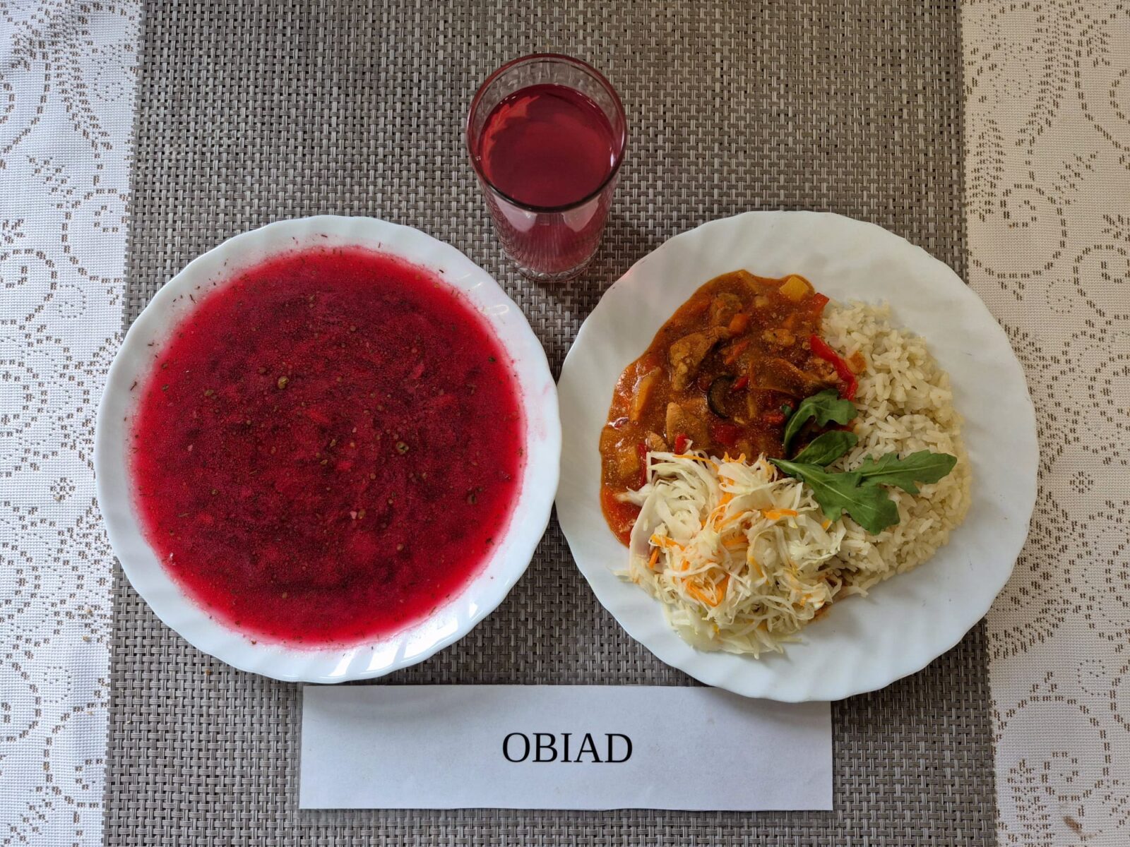 Na zdjęciu znajduję się posiłek w którego skład wchodzi Barszcz ukraiński z fasdolą białą i ziemniakami, Ryż biały, Wieprzowina w sosie słodko-kwaśnym, Surówka z kapusty białej w zalecie octowej, Kompot z jabłek