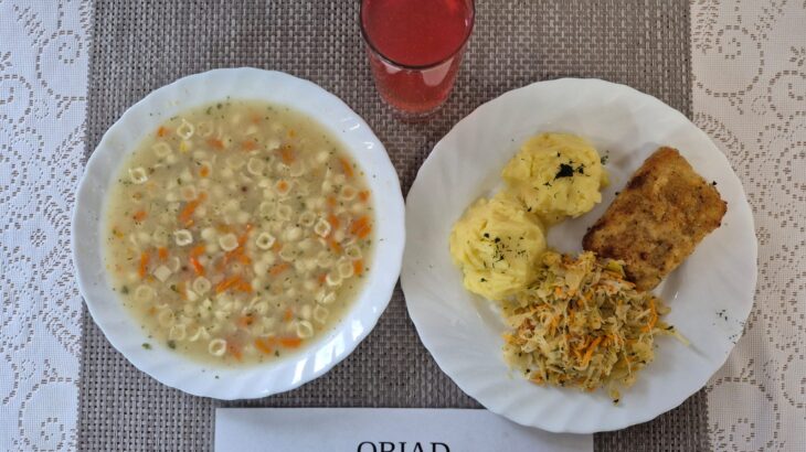 Na zdjęciu znajduję się posiłek w którego skład wchodzi Zupa kalafiorowa z ziemniakami, Ryba panierowana, smażona, Surówka z kapusty kiszonej z dodoatkiem oleju rzepakowego oraz kompot z jabłek