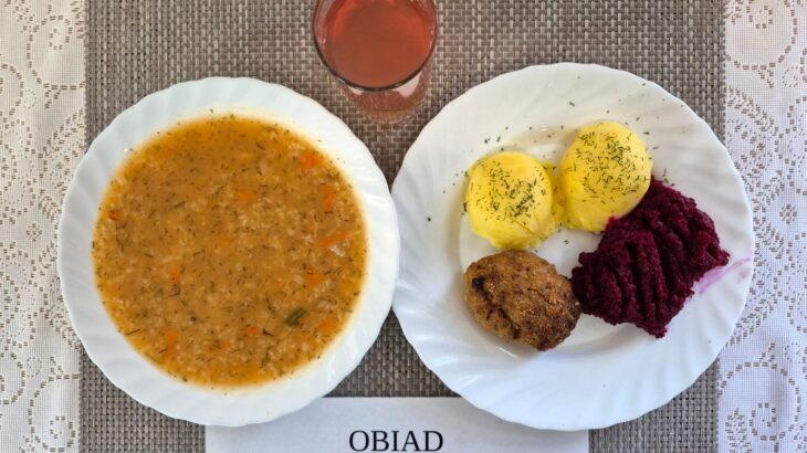 Na zdjęciu znajduję się posiłek w którego skład wchodzi Zupa pomidorowa z ryżem białym, Ziemniaki, Sznycel wieprzowy, Ćwikła oraz Kompot z jabłek