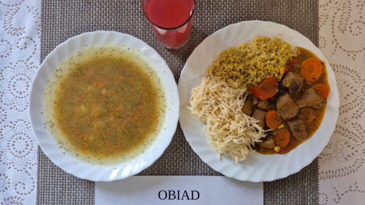 Na zdjęciu znajduję się posiłek w którego skład wchodzi Zupa ziemniaczana, Kasza bulgur, Gulasz drobiowy z kukurydzą , papryką i pieczarkami, Surówka z selera, gruszka oraz Kompot z jabłek