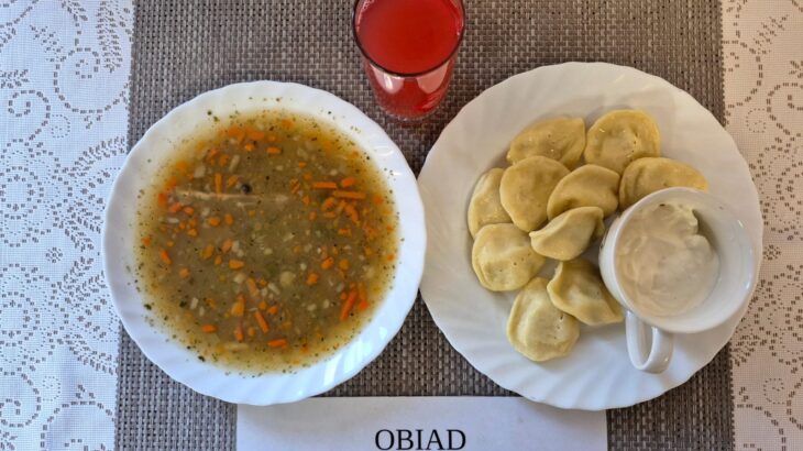 Na zdjęciu znajduję się posiłek w którego skład wchodzi Zupa grochowa z ziemniakami, Pierogi, kefir oraz kompot z jabłek