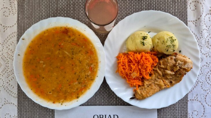 Na zdjęciu znajduję się posiłek w którego skład wchodzi Zupa pomidorowa z ryżem białym, Ziemniaki, gotowane, Pierś z kurczaka panierowana, smażona, Surówka marchewki i ananasa, jabłko, Kompot z jabłek