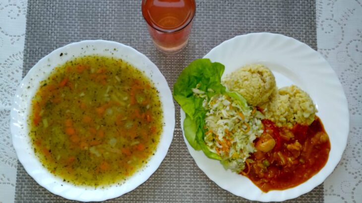 Na zdjęciu znajduję się posiłek w którego skład wchodzi Zupa grochowa z ziemniakami, Gulasz z indyka z warzywami, Surówka z kapusty pekińskiej z marchewką oraz kompot