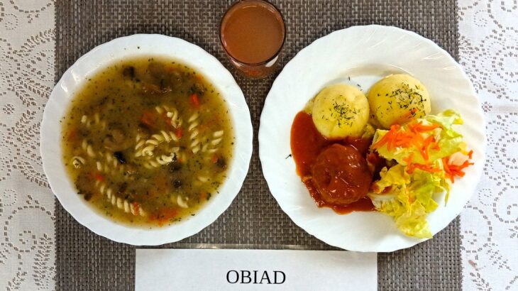 Na zdjęciu znajduję się posiłek w którego skład wchodzi: Zupa pieczarkowa z makaronem, Ziemniaki, gotowane, Pulpet pieczony w sosie pomidorowym. Sałatka z sałaty masłowej i marchewki z dodatkiem sosu vinegret oraz Kompot z jabłek