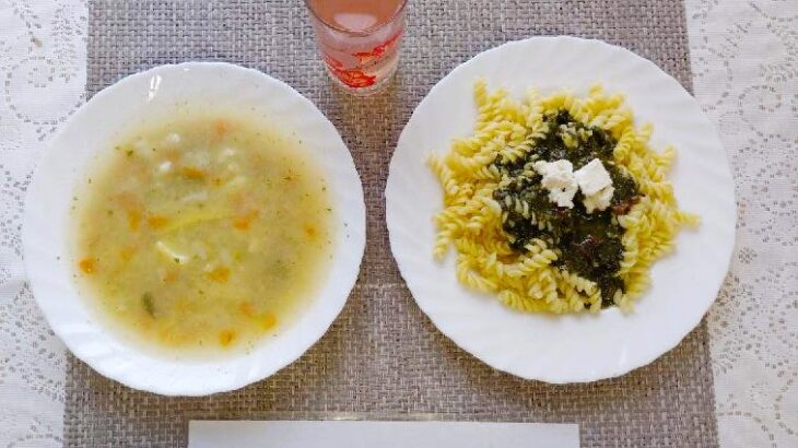 Na zdjęciu znajduję się posiłek w którego skład wchodzi Zupa kalafiorowa ziemniakami i i makaronem, Ryba smażona, Surówka z kiszonej kapusty, kompot, Jabłko