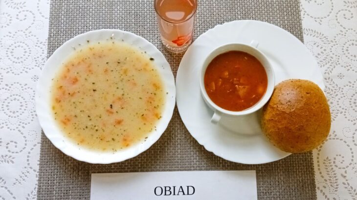 Na zdjęciu znajduję się posiłek w którego skład wchodzi Zupa żurek z ziemniakami, Fasolka po bretońsku, Bułka pszenna, Kompot z jabłek