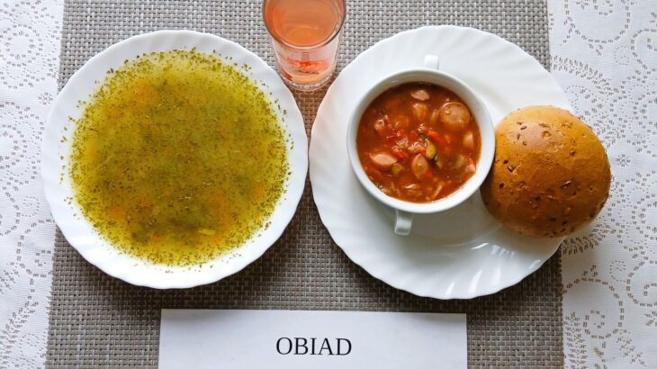 Na zdjęciu znajduję się posiłek w którego skład wchodzi Zupa ziemniaczana, Leczo z kiełbasą parówkową, Bułka wieloziarnista, kompot z jabłek, Gruszka